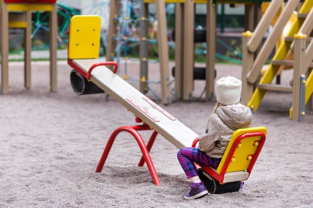 A girl sits at one end of a seesaw