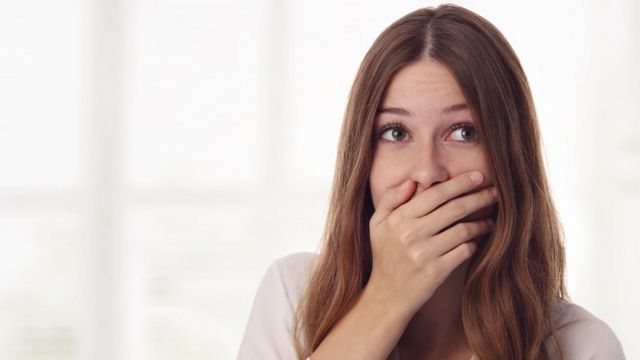 Mujer tapándose la boca.