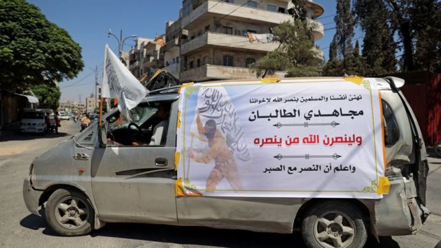 سيارة تابعة لأعضاء في تحالف "هيئة تحرير الشام"، بقيادة فرع القاعدة السابق في سوريا، تحمل لافتة تهنئ طالبان على سيطرتهم على أفغانستان في مدينة إدلب الشمالية الغربية في 20 أغسطس/ آب 2021.