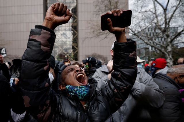 A person raises their arms after the verdict in the trial of former Minneapolis police officer Derek Chauvin, in front of Hennepin County Government Center, in Minneapolis, Minnesota
