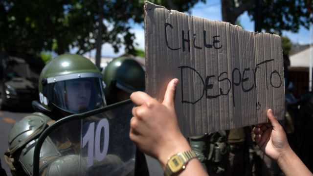 "Chile despertó", dice un cartel frente a los policías.