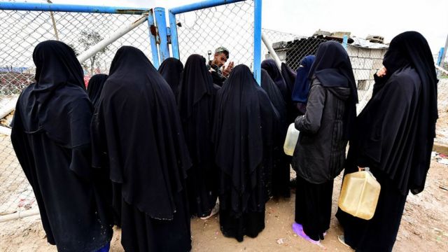 Veiled women, living in al-Hawl camp in Syria which houses relatives of Islamic State (IS) group members, stand in queue to receive aid on March 28, 2019