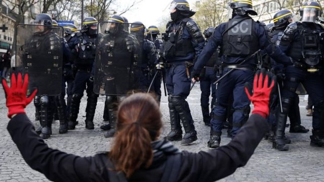 Протестующая поднимает руки в красной краске на фоне полицейских