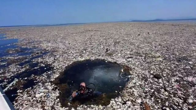 Homem mergulha em mar de lixo