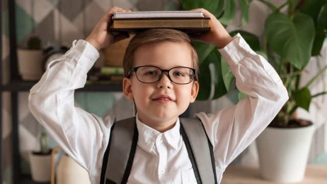 Un niño con gafas y libros