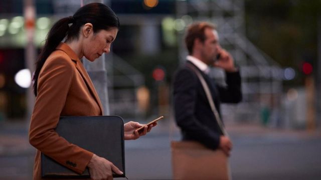 امرأة تنظر إلى هاتفها المحمول وهي تخرج من مقر العمل