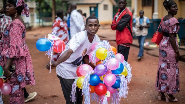 Wani mutum rike da tarin balan-balan da ake bai wa 'yan uwa da abokan arziki a kofar ofoshin magajin garin Bangui , a jamhuriar tsakiyar Afurka a ranar Lahadi 20 Maris 2021.