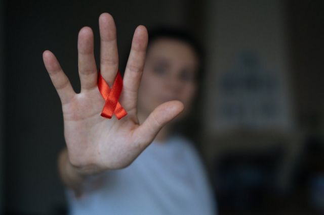 Mujer con el lazo rojo de la lucha contra el VIH/sida.