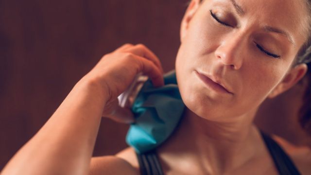 Mujer poniéndose hielo en el cuello