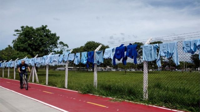 Dezenas de camisas de trabalho penduradas em cerca de fábrica