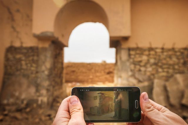 A picture taken on 15 November 2016 shows a phone with a picture of the ancient ruins of Nimrud before and after their destruction by IS militants