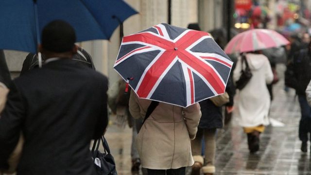 Прохожий с зонтиком в цветах британского флага на лондонской улице