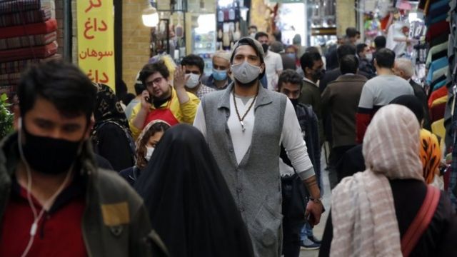 المارة في أحد شوارع طهران يرتدون الكمامات