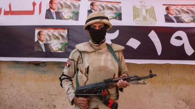 An Egyptian soldier in front of a picture of President Abdel Fattah El-Sisi