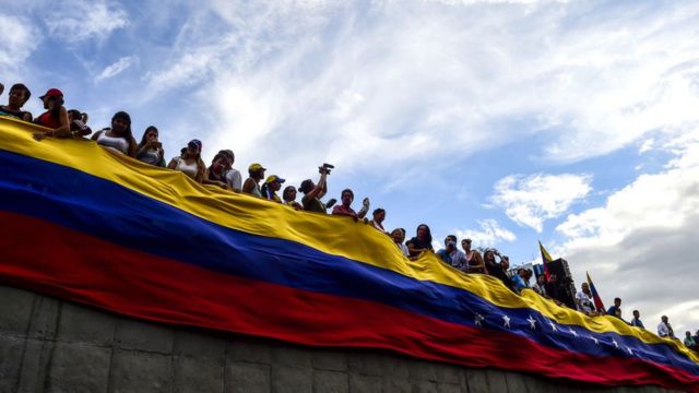 Bandera de Venezuela con personas sobre ella.
