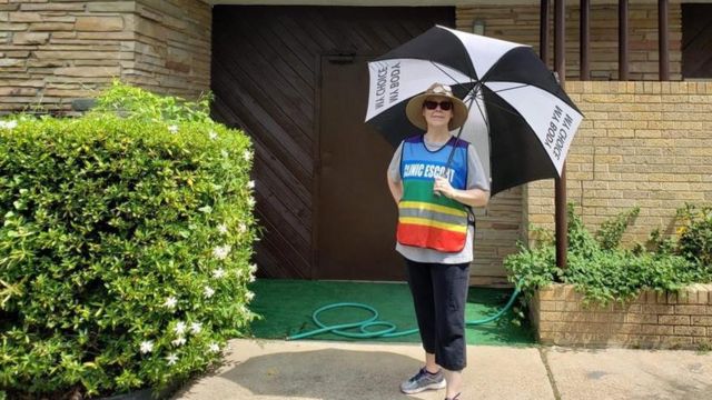ريبيكا أمام عيادة "هوب مديكال غروب" وتحمل مظلة كتب عليها "جسدي هو خياري"