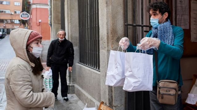 Una mujer recibe unas bolsas con comida en Madrid.