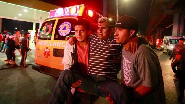Dos hombres trasladan a un herido en el accidente del metro de Ciudad de México