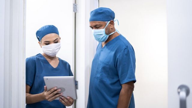 Enfermeiros com equipamentos de proteção conversam em hospital