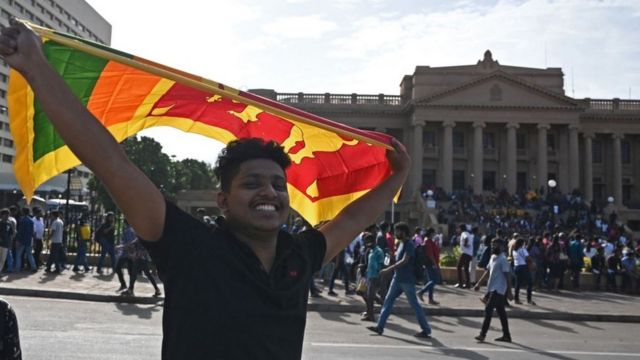 Un hombre ondea la bandera nacional de Sri Lanka frente a la secretaría presidencial en Colombo el 13 de julio de 2022.