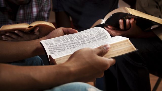 Close nas mãos de pessoas segurando biblias em uma roda de conversa