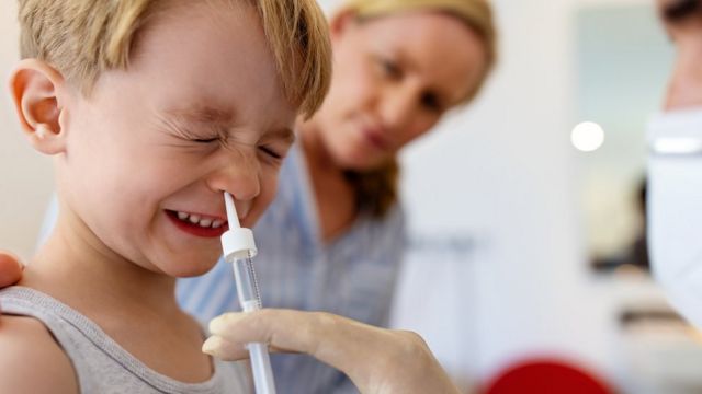 Un niño recibe una dosis de un medicamento vía intranasal