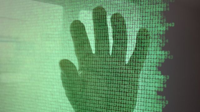 silueta de una mano sobre un código binario