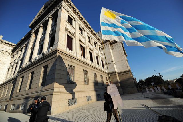 Un hombre sostiene una bandera fuera del Parlamento uruguayo en Montevideo.