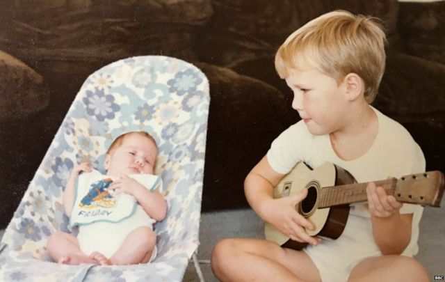 Robyn as a baby with her older brother Gareth serenading her on his guitar