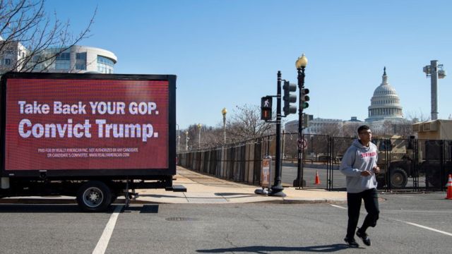 رجل يجري بجانب شاحنة وعليه لافتة كتب عليها "استعيدوا الحزب الجمهوري. أدينوا ترامب% بالقرب من مبنى الكابيتول في واشنطن
