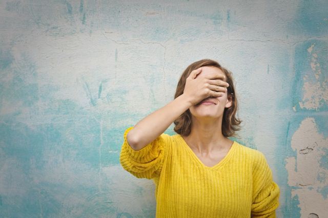 Woman putting her hand on her eyes, as if she's regretting having made a mistake
