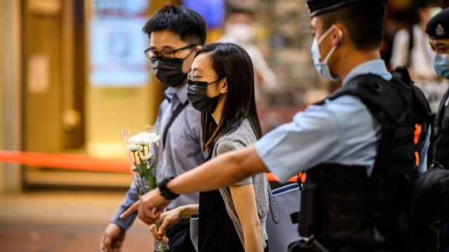 Police officers outside Sogo Department Store in Causeway Bay, Hong Kong drive away a man and woman holding white chrysanthemums (2/7/2021)