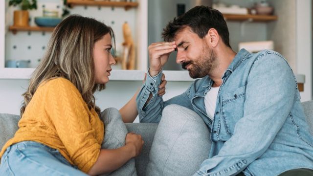 Un hombre con aspecto preocupado habla con una mujer.