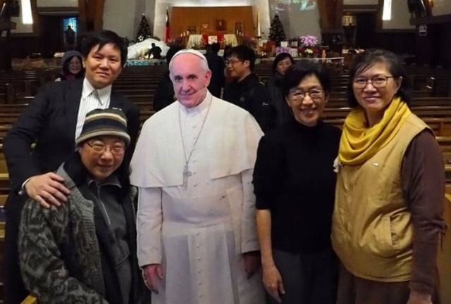 In Taiwan, people pose for pictures with a cardboard cutout of Pope Francis in the Catholic Holy Family Church in Taipei