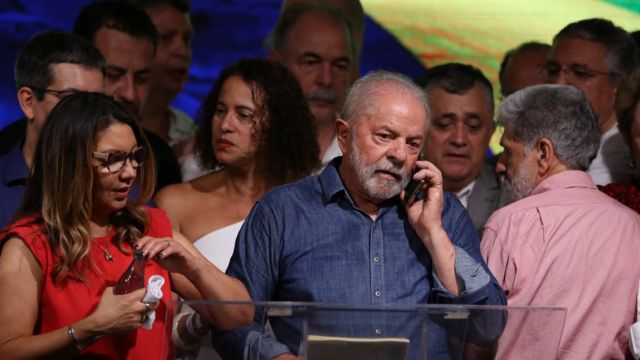 Lula talking on his cell phone, in the midst of several people around him