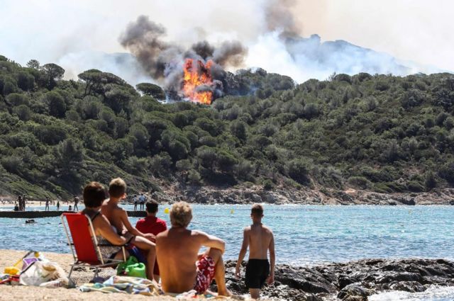 People on the beach watch a forest fire in La Croix-Valmer, near Saint-Tropez, on 25 July 2017.