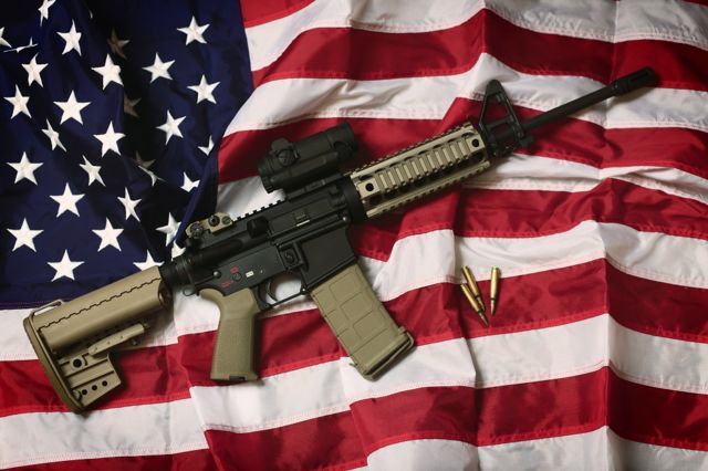 Um rifle AR-15 com balas em uma bandeira americana