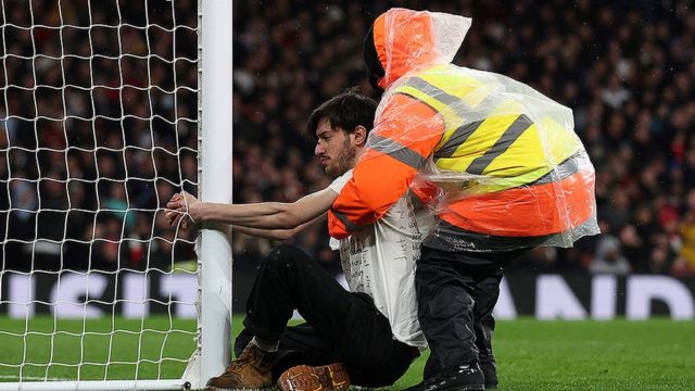 Arsenal-Liverpool maçında kendini kale direğine yapıştıran bir protestocu