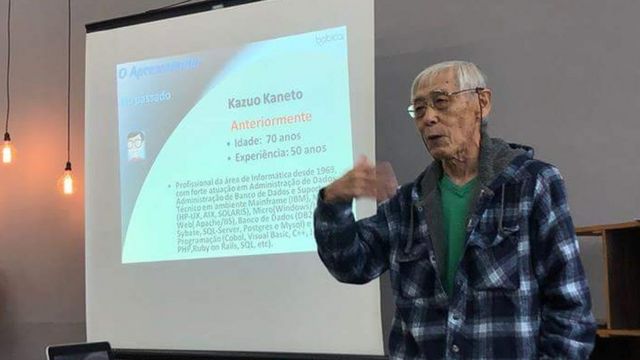 Kazuo Kaneto dá palestra, apresentando slide em tela