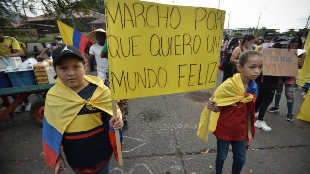 Niñas marchando en una protesta en Colombia sosteniendo un cartel con la leyenda: "Marcho porque quiero un mundo feliz".
