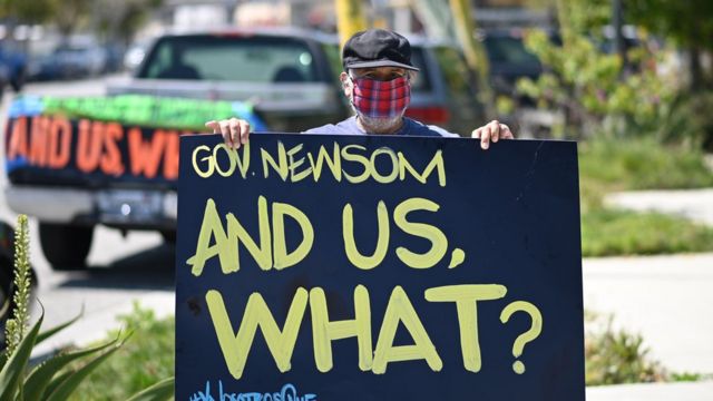 Un hombre con un cartel dirigido al gobernador de California en el que le pregunta: ¿Y nosotros qué?