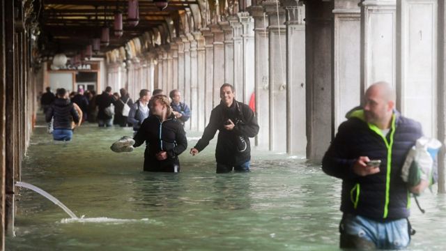 Tourists walk through flooded St Mark Square in Venice on 29 October 2018