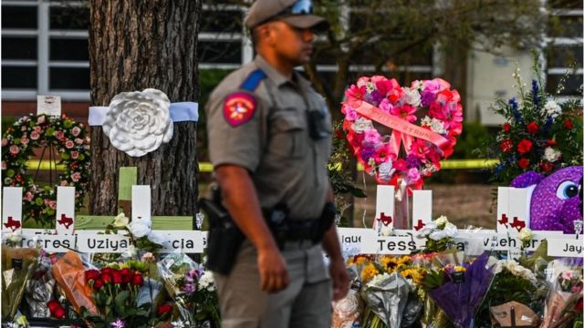 Police in front of crosses to honor those killed in the Uvalde, Texas, school shooting.