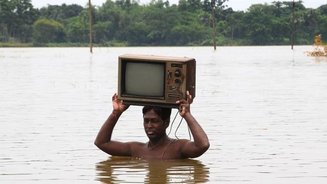 An Indian carries a TV through flood waters in Howrah district in the state of West Bengal.