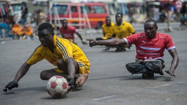 Hombres que fueron afectados con polio juegan con una pelota en Ghana.