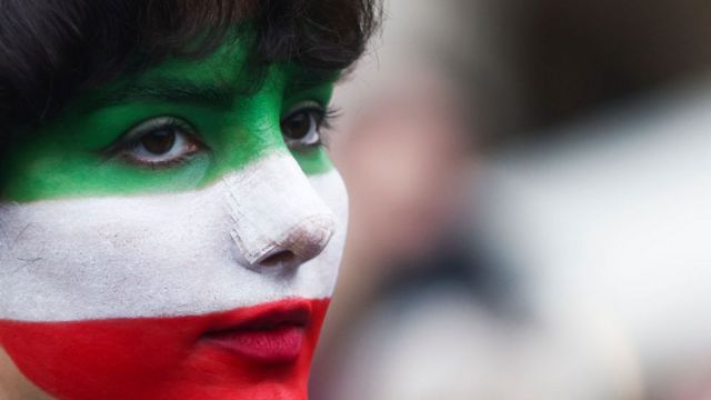 Kobieta z twarzą pomalowaną na kolory flagi Iranu w Polsce.