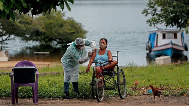 Mulher é vacinada por profissional de saúde