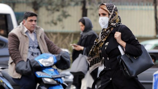 A woman wearing a face mask walks on a street in Tehran, Iran (22 February 2020)