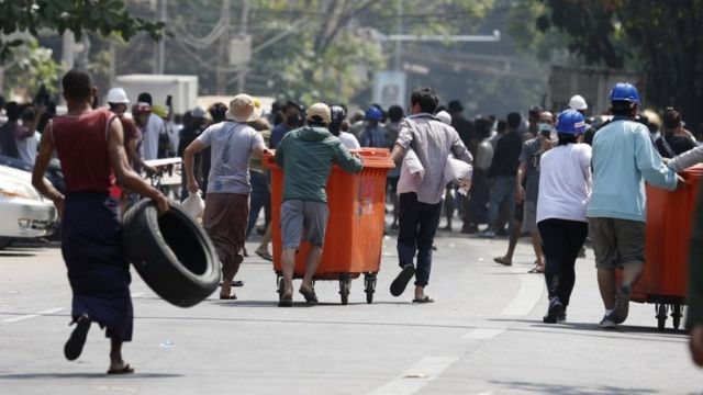 Demonstrators move rubbish bins and tires to build barricades during a protest