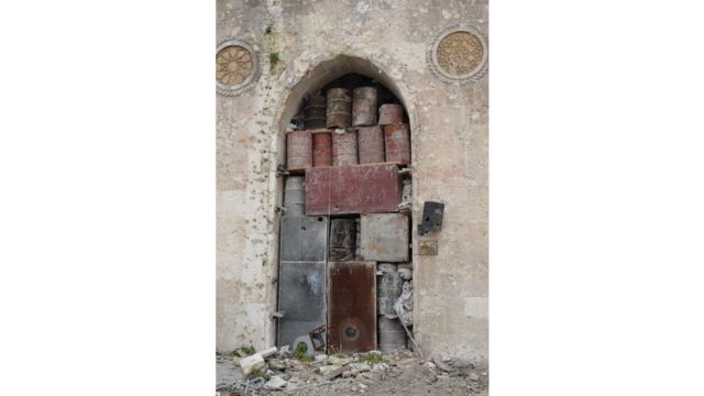 Barriles y cajas apiladas en un arco para evitar los daños de los bombardeos